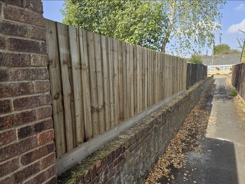 New closeboard fence running above a brick wall beside an alleyway