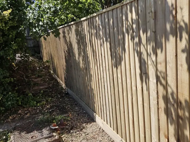 Finished closeboard fence with gravel boards running under trees