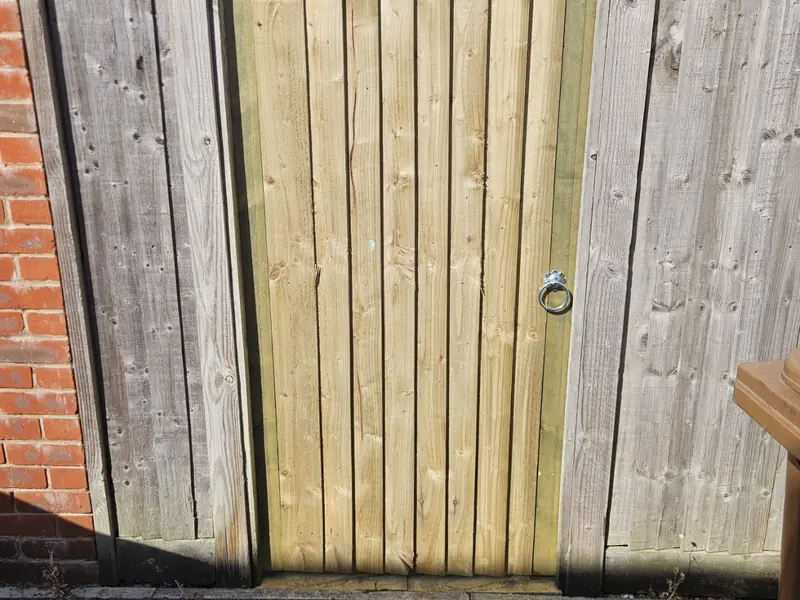 New closeboard gate with a ring latch set between older weathered fence panels