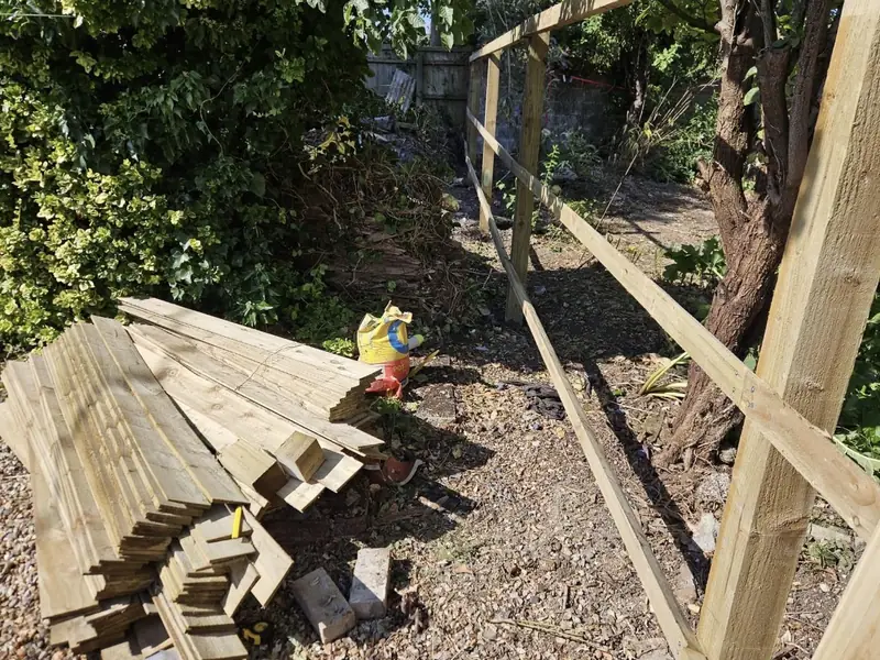 Fence posts and rails in place with featheredge boards stacked ready to fit