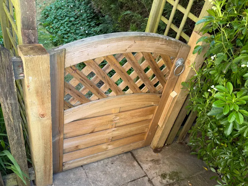 Timber garden gate with a curved lattice top and ring latch