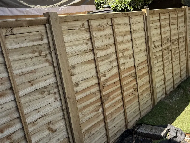 New lap panel fence on timber posts running along a garden