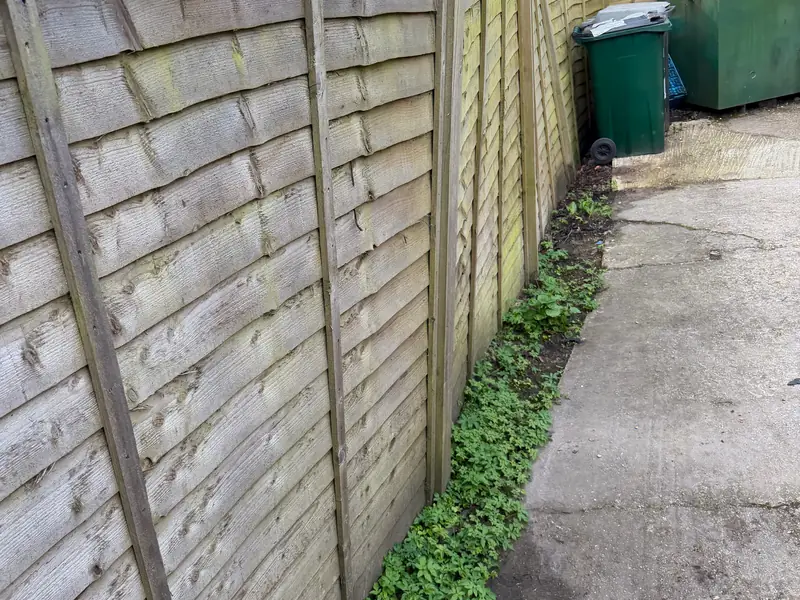 Old lap panel fence with tired posts before repair